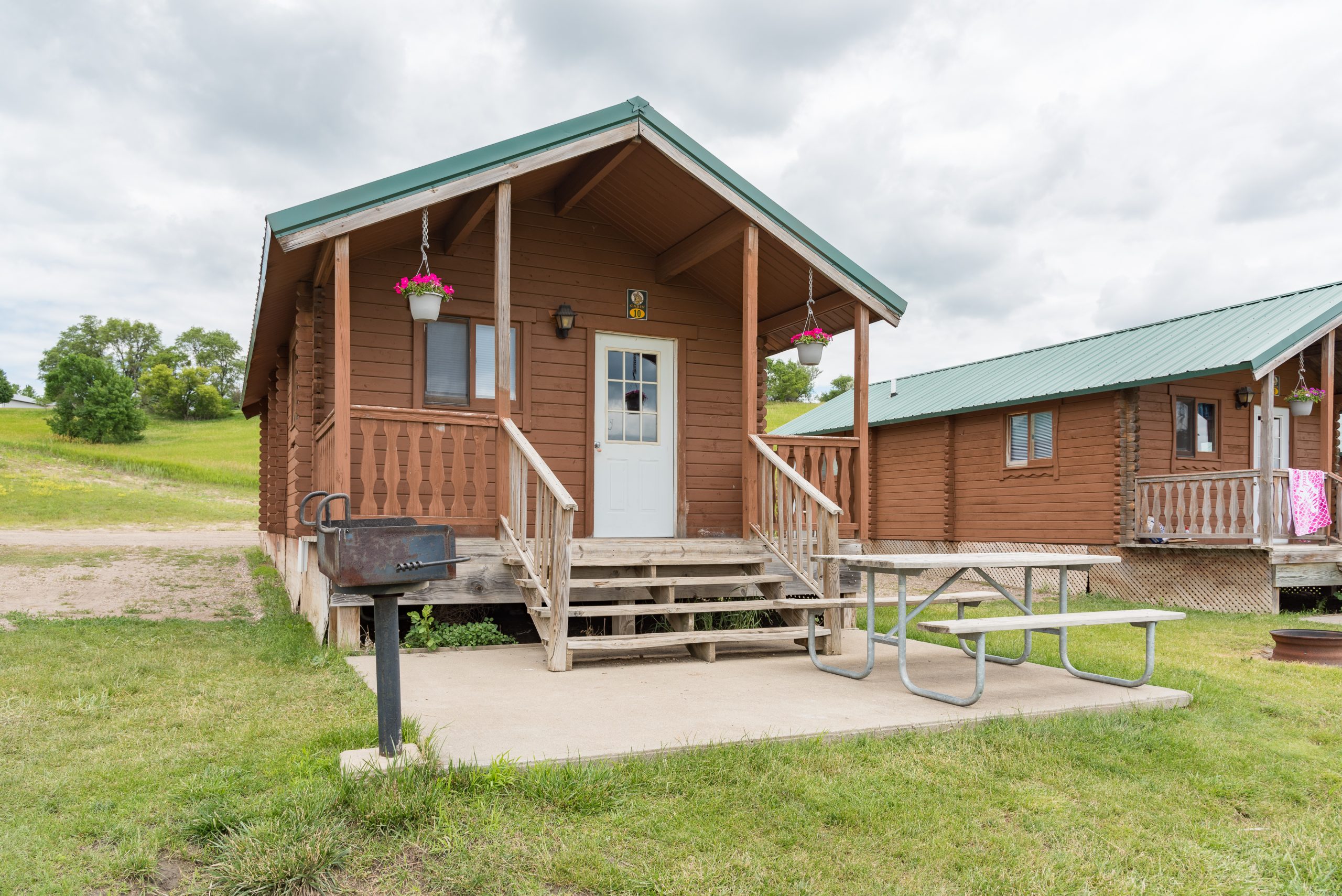 Front of Cottage style cabin, cement patio with table and charcoal grill